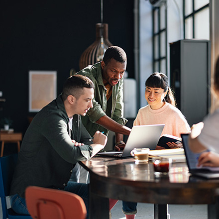 A group of three colleagues working on a laptop